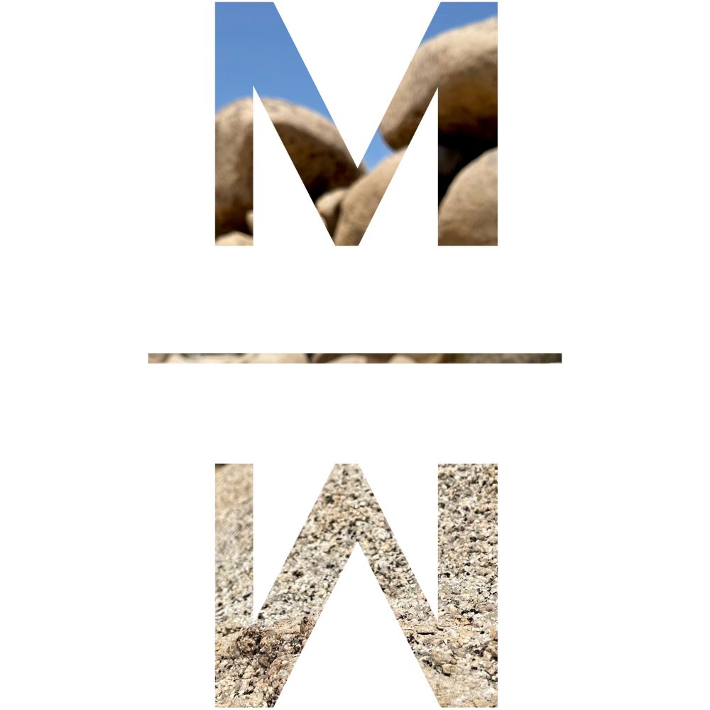 The Mojave Myst MM icon with white tank monzogranite rocks and blue sky coloring in its letter shapes.