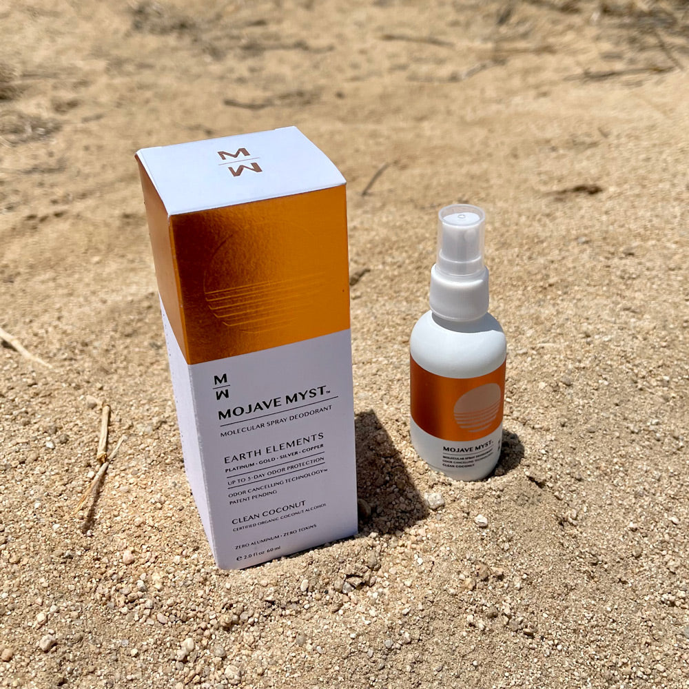 
                  
                    A luxury box of Mojave Myst Molecular Spray Deodorant with a spray bottle next to it sitting on desert sand.
                  
                
