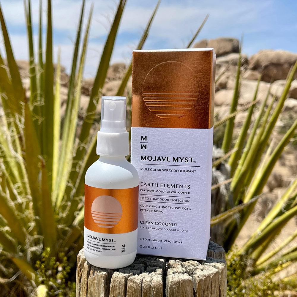 
                  
                    A luxury box of Mojave Myst Molecular Spray Deodorant with a spray bottle next to it. They are placed on the edge of a log post and Mojave Yuccas are in the background.
                  
                